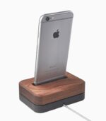 Smartphone on wooden charging dock.