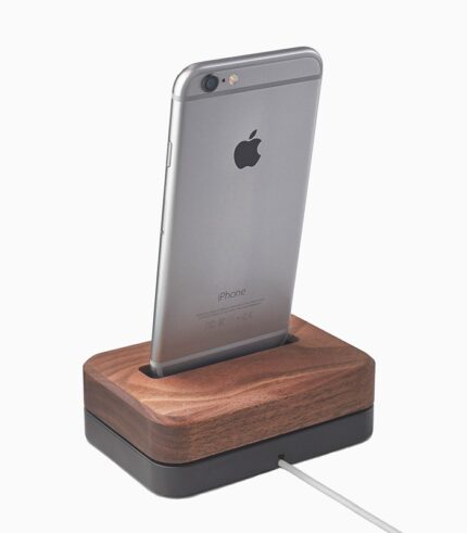 Smartphone on wooden charging dock.