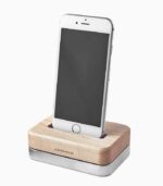 Smartphone on wooden charging dock stand.