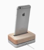 Smartphone on wooden charging dock, white background.