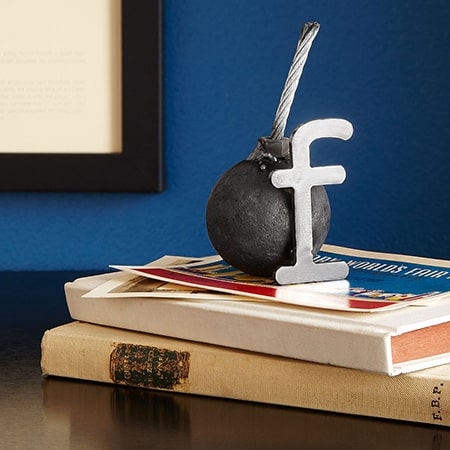 Letter F bomb sculpture on stacked books.