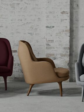 Three modern upholstered chairs against brick wall.