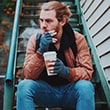 Man sitting on steps with coffee.