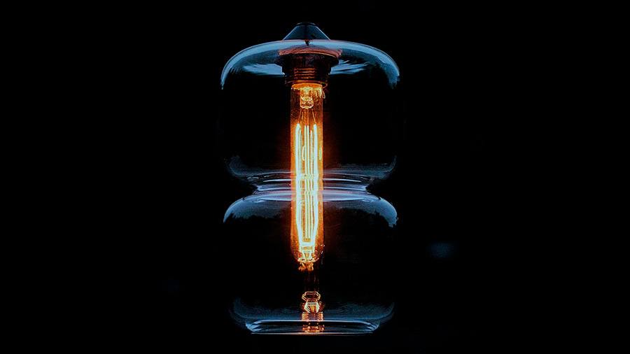 Glowing light bulb against dark background.