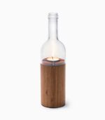 Wine bottle candle holder with lit candle.