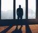 Silhouette of person looking out large window.
