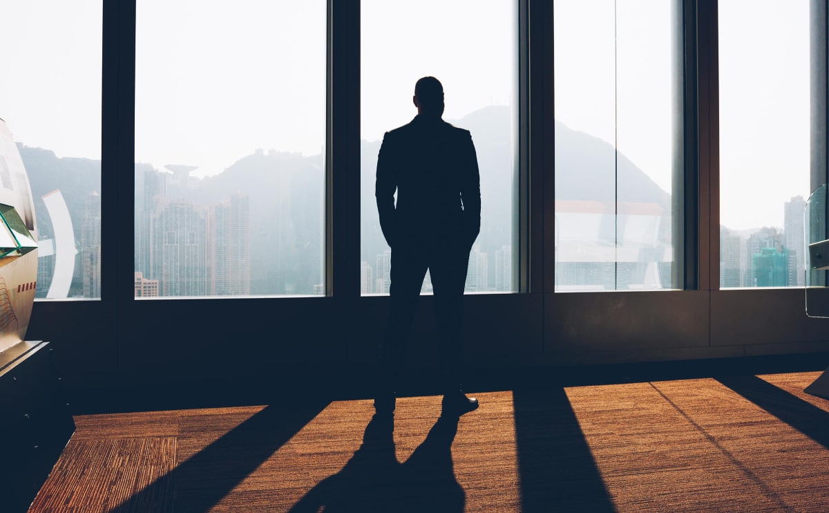 Silhouette of person looking out large window.