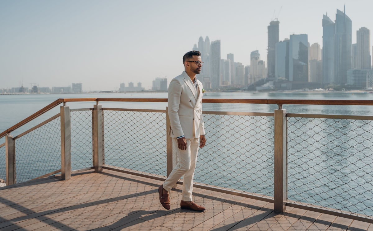 Man in suit walking by waterfront cityscape.