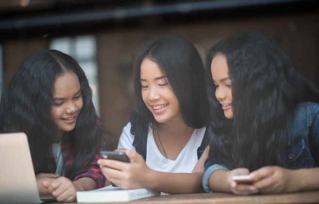 Three girls smiling at smartphone together.